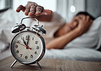 Alarm, morning and a hand with a clock for awake, oversleep or tired in the bedroom of a home. House, ring and a closeup of a person or woman in bed for snooze, rest or waking up lazy in a house