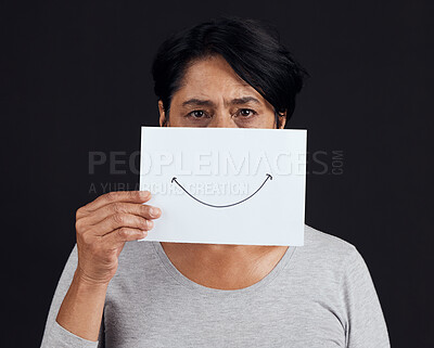 Buy stock photo Portrait, fake smile or depression and a mature woman in studio on a dark background with an expression. Abuse, anxiety and mental health with a female person looking brave to hide her emotions