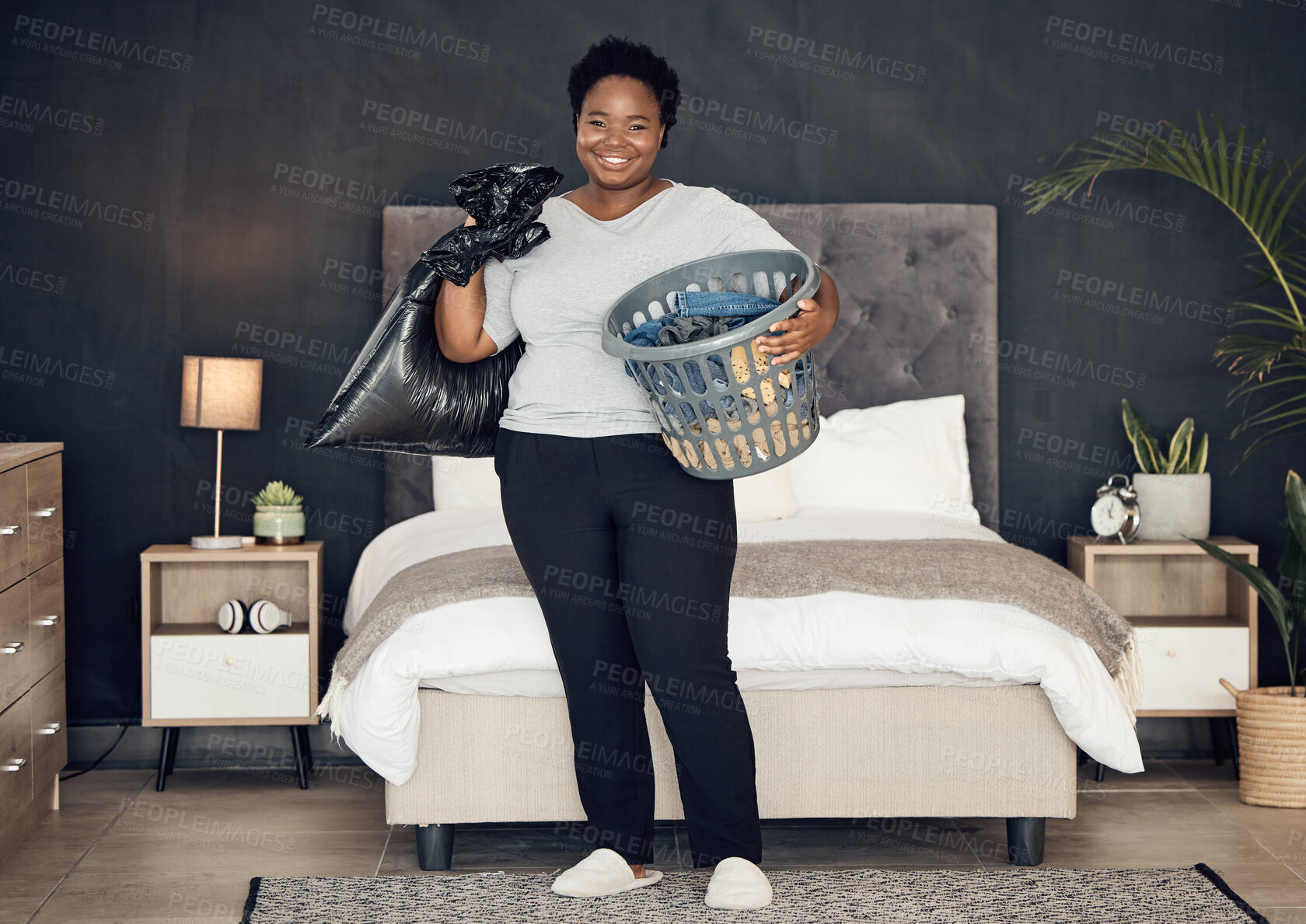 Buy stock photo Black woman, clothes in basket and cleaning bedroom, garbage bag and hygiene with portrait in bedroom. Female person, cleaner and housekeeping with smile, laundry and maintenance with morning routine