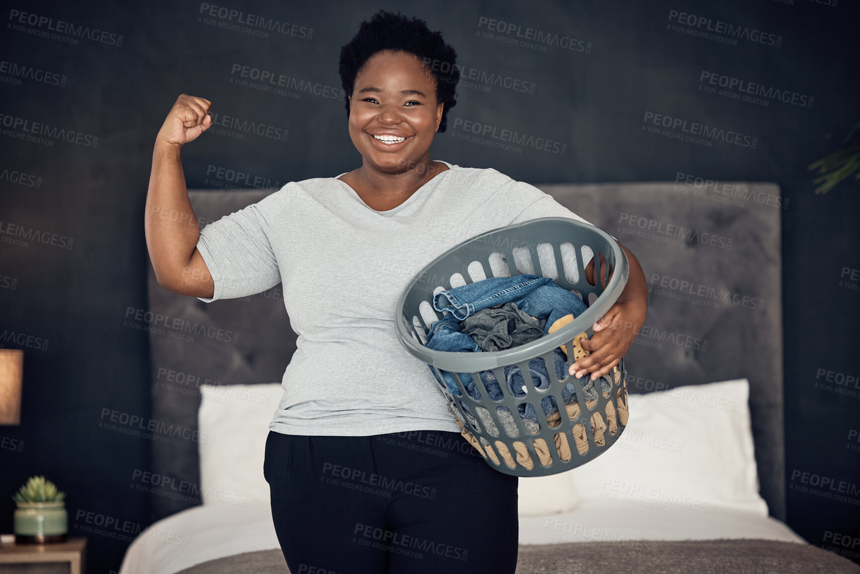 Buy stock photo Black woman, clothes in basket and champion, success in cleaning and bedroom with hygiene in portrait. Strong female cleaner, winner at housekeeping with smile, laundry and maintenance at home