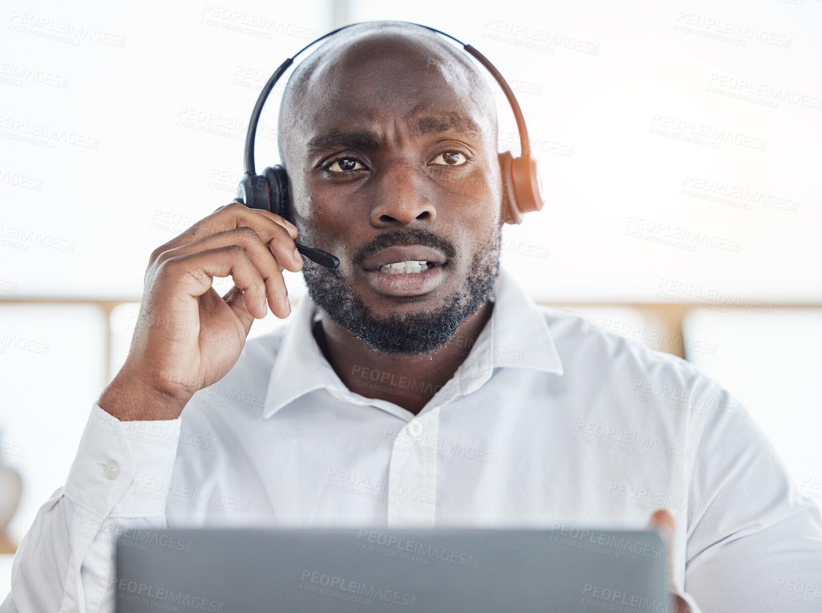 Buy stock photo Black man thinking while consulting on laptop in call center for customer service, advisory and questions. Face of serious salesman working in CRM agency for telecom solution, tech support and help