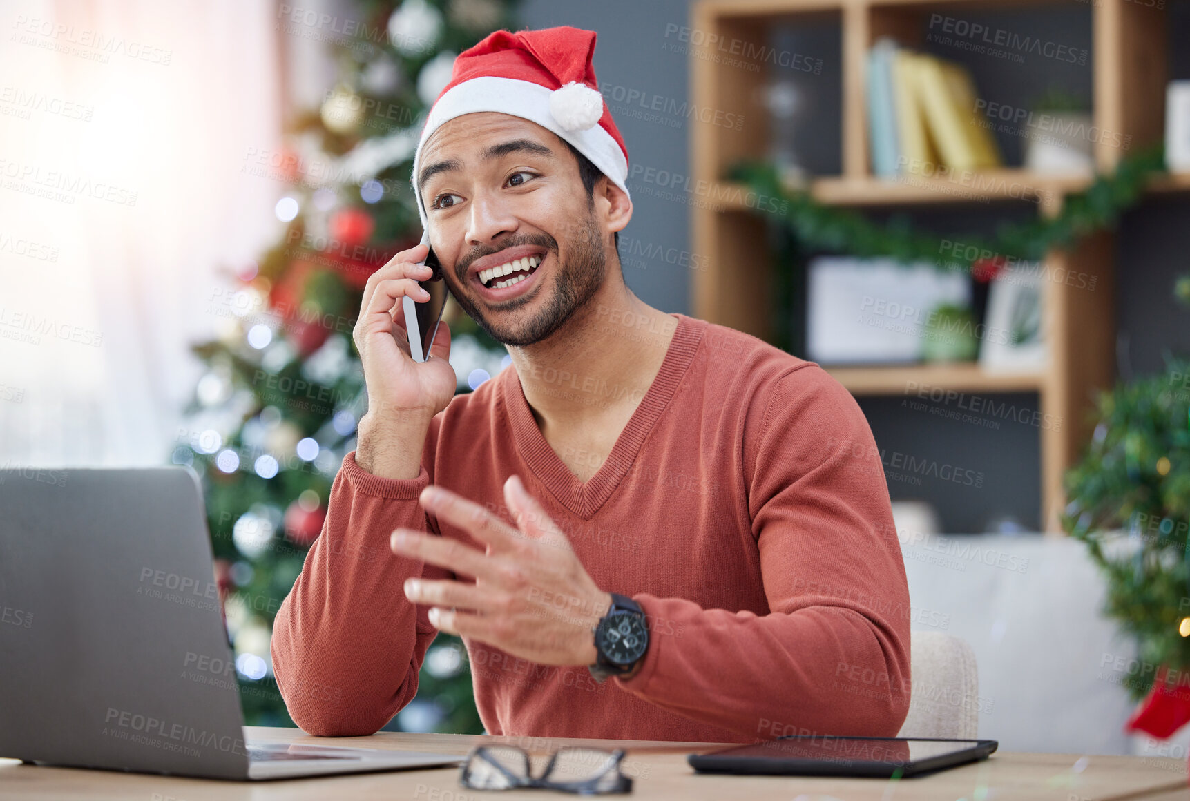 Buy stock photo Phone call, christmas hat and man in the office with a laptop on a cellphone for communication. Happy, smile and young male creative designer with xmas decorations on mobile conversation in workplace