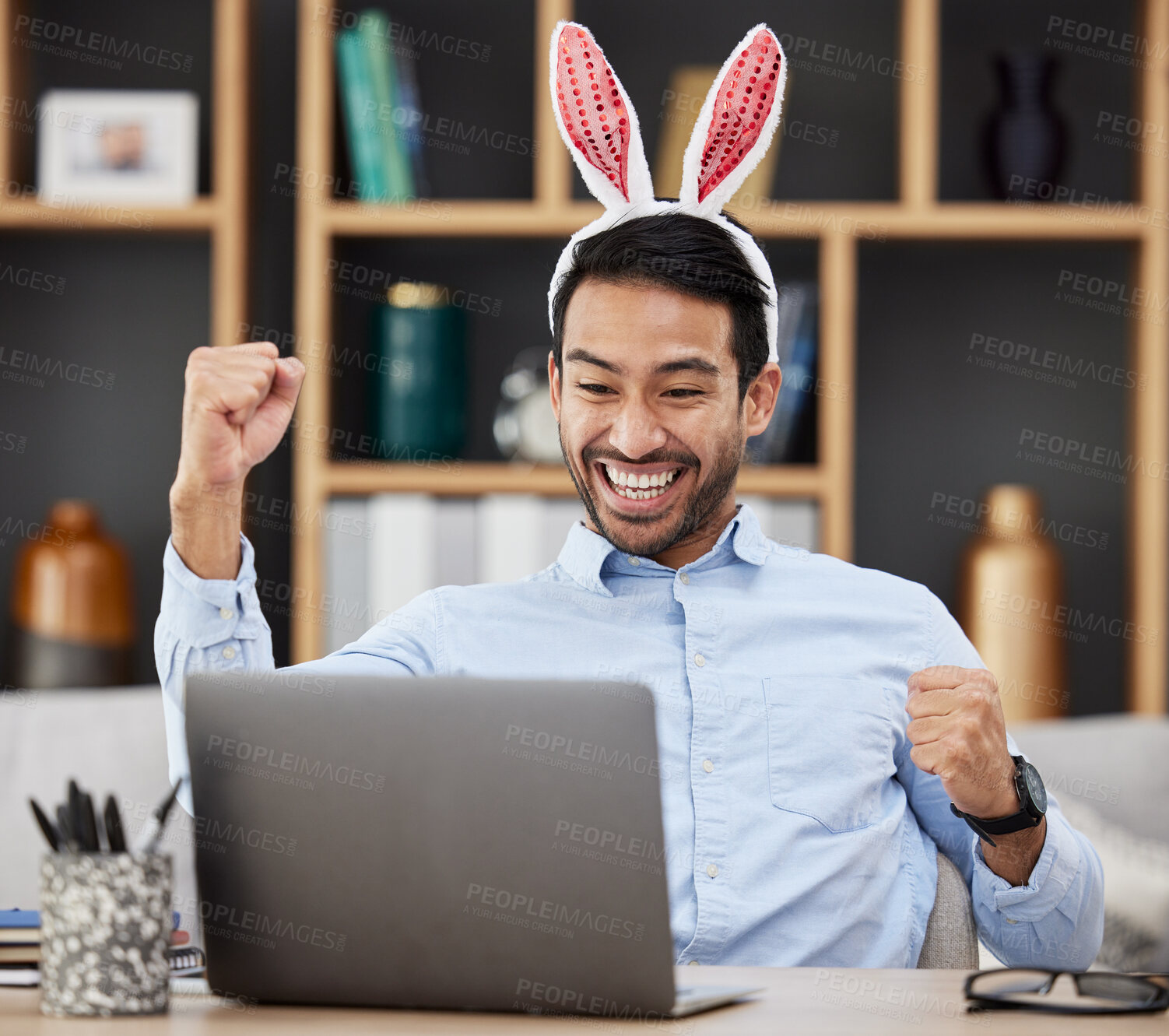 Buy stock photo Bunny ears, easter and winning by business man excited, happy and celebrate in an office with success. Winner, rabbit and employee or person with victory, achievement and using a laptop for profit