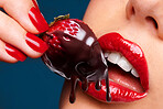 Chocolate, strawberry and closeup of lips with woman and eating for candy, sweets and dessert. Makeup, cosmetics and confectionery with mouth of person on blue background for fruit, food and treat