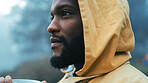 Coffee, morning and black man hiking in the woods with a blurred background of cold, winter weather. Thinking, raincoat and face of a young male hiker in the forest or nature to explore for adventure