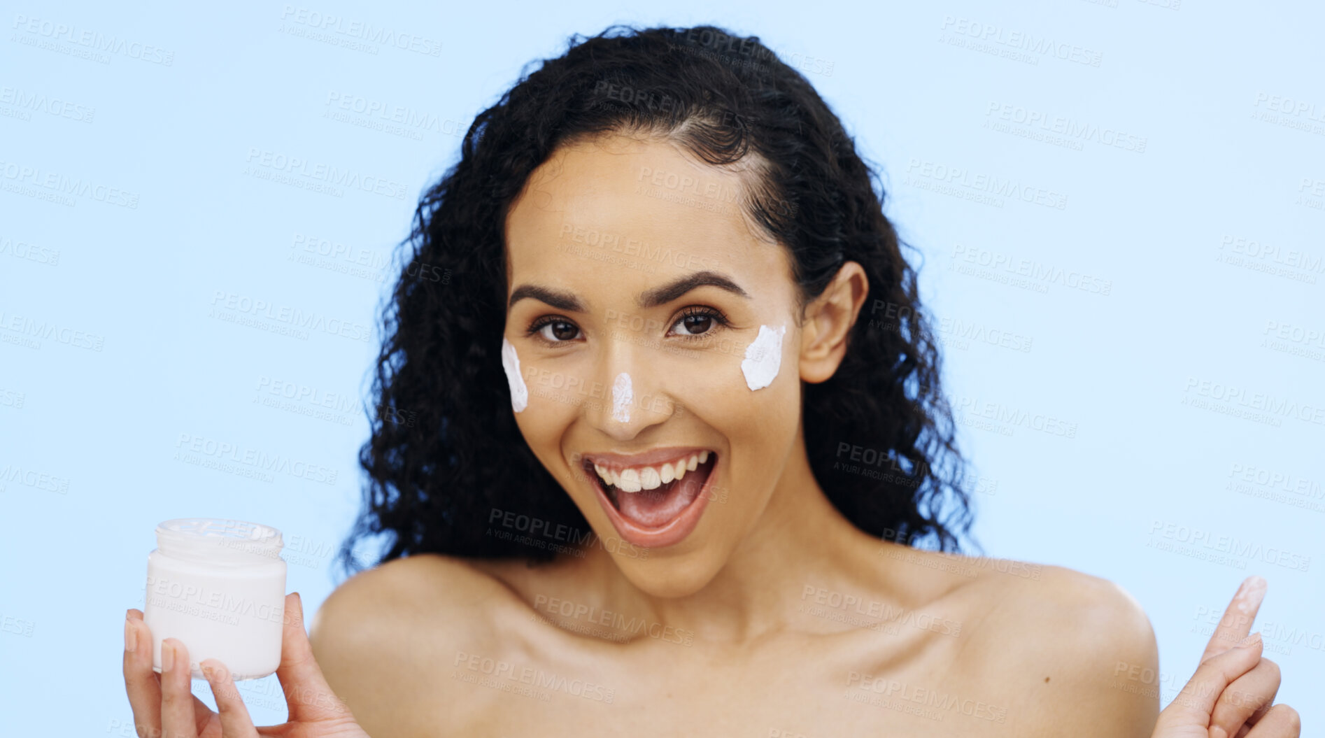 Buy stock photo Face, cream and beauty of woman with cosmetics, smile and sunscreen on blue background. Facial skincare, lotion jar and portrait of happy model with product for shine, happiness and aesthetic makeup