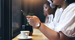 Cafe, phone and closeup of a woman typing a text message on the internet or social media. Technology, cup of coffee and young female person doing research or browsing on her cellphone in a restaurant