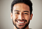 Face, portrait and smile of happy asian man in studio with positive mindset, wellness and awareness. Face of a young male model isolated on a grey background with happiness and unique identity