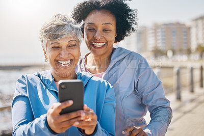 Buy stock photo Senior woman, daughter and outdoor with phone or reading social media, blog or post about workout or walk in the park. Elderly mother, girl and profile picture on the beach or together on screen