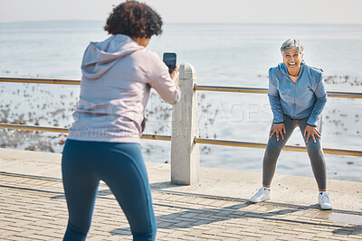 Buy stock photo Phone, photograph and friends laugh of senior women at beach with funny joke at sea for fitness. Exercise, mobile and picture for social media post on ocean promenade walk for workout and friendship