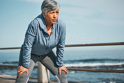 Buy stock photo Senior, fitness and tired woman at the beach on break from training, workout or morning cardio run in nature. Sports, fatigue and elderly female runner stop to breathe on ocean workout or performance