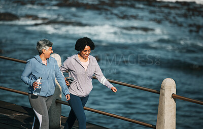 Fitness, exercise and senior women by ocean for healthy body, wellness and cardio on promenade. Sports, friends and female people with water bottle on boardwalk for walking, training and workout