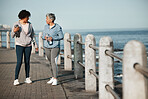 Fitness, walking and women by ocean talking for healthy lifestyle, wellness and cardio on promenade. Sports, friends and female people in conversation on boardwalk for exercise, training and workout