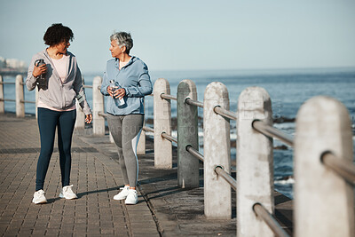 Buy stock photo Fitness, walking and women by ocean talking for healthy lifestyle, wellness and cardio on promenade. Sports, friends and female people in conversation on boardwalk for exercise, training and workout