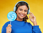 Woman, lollipop and headphones in studio portrait, smile or choice for radio, podcast or music by yellow background. Happy gen z girl, student and candy with streaming subscription, sugar and fashion