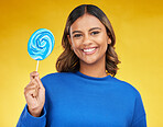 Happy, candy and portrait of a woman, lollipop and positive girl on a yellow studio background. Face, female person or model with sweets, snack and fun with mockup space, cheerful or joy with freedom