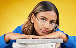 Woman, student and books in studio portrait with glasses, financial education and commitment by yellow background. Gen z girl, learning and studying economy with mindset, knowledge and development