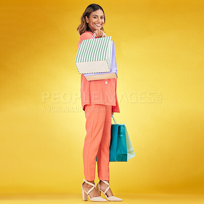Buy stock photo Portrait, happy woman and shopping bag in studio for clothes, retail deal and financial freedom on yellow background. Indian customer, gift bags and discount from fashion store, sales and promotion 