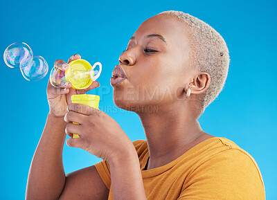 Buy stock photo Woman, blowing bubbles and fun in studio, blue background or party celebration with fun, liquid soap or toy. African girl, person and relax with happy, joyful or creative break for college student