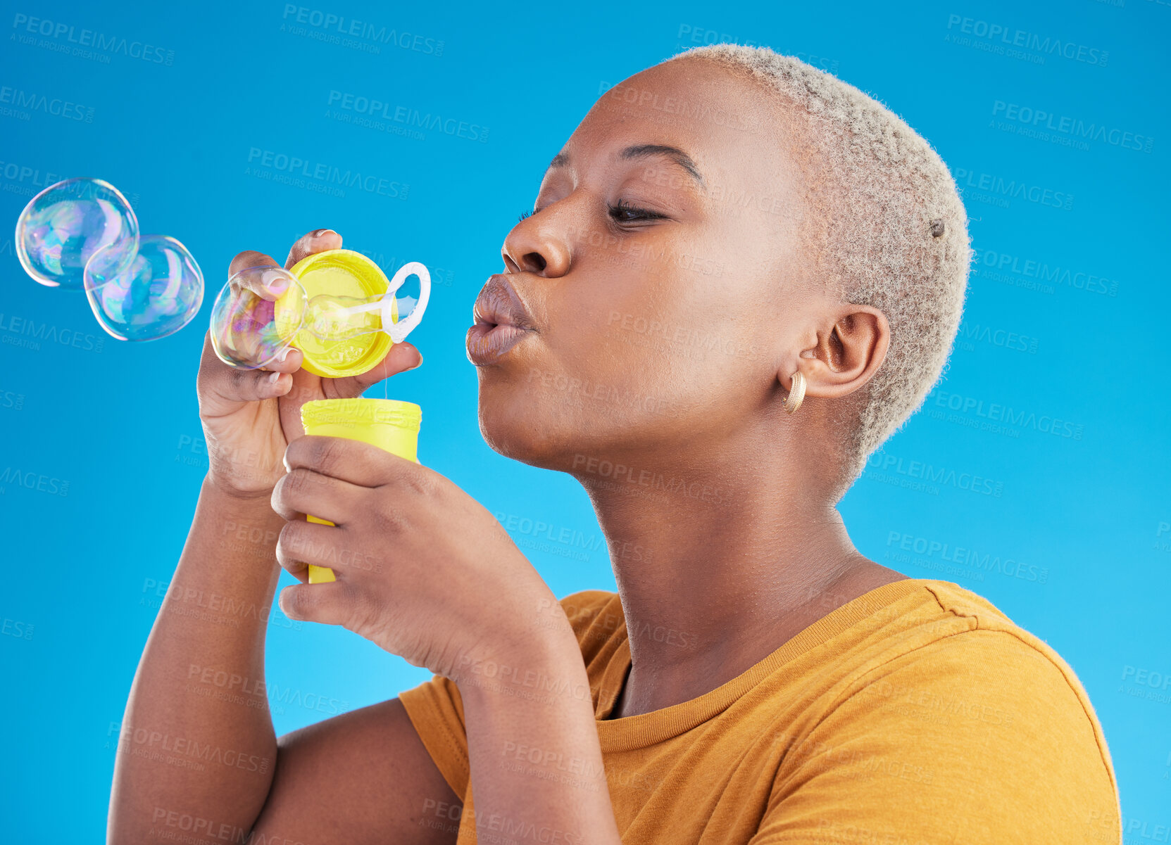 Buy stock photo Woman, blowing bubbles and fun in studio, blue background or party celebration with fun, liquid soap or toy. African girl, person and relax with happy, joyful or creative break for college student