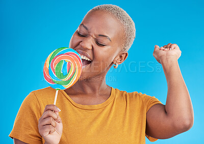 Buy stock photo Lollipop, singing and a woman with candy in studio for sweets, rainbow and creative advertising. Happy black female person isolated on a blue background with sugar, freedom and happiness or color