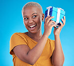 Shake gift, excited black woman with box and studio isolated on a blue background. Curious, happy and African person with present for party, celebration of holiday or birthday package for giveaway