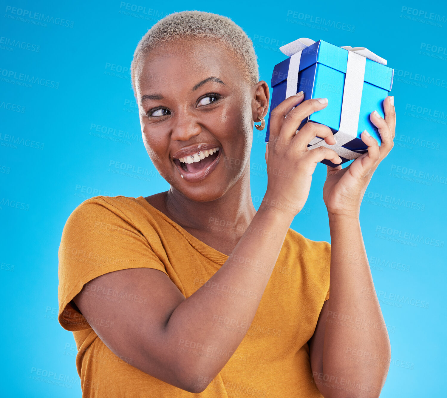 Buy stock photo Shake gift, excited black woman with box and studio isolated on a blue background. Curious, happy and African person with present for party, celebration of holiday or birthday package for giveaway