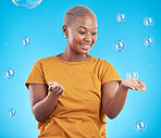 Black woman, playing with bubbles and happiness, fun and vibrant with entertainment on blue background. Liquid soap, freedom and African female person, playful with activity and enjoy in studio