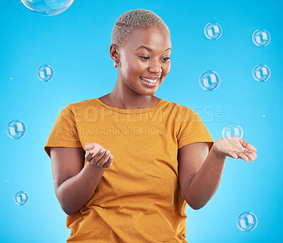 Buy stock photo Black woman, playing with bubbles and happiness, fun and vibrant with entertainment on blue background. Liquid soap, freedom and African female person, playful with activity and enjoy in studio