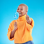Thumbs up, lollipop and black woman in portrait with candy in studio isolated on a blue background. African person, happy face and sweets, dessert and sugar food with like hand sign for excellence