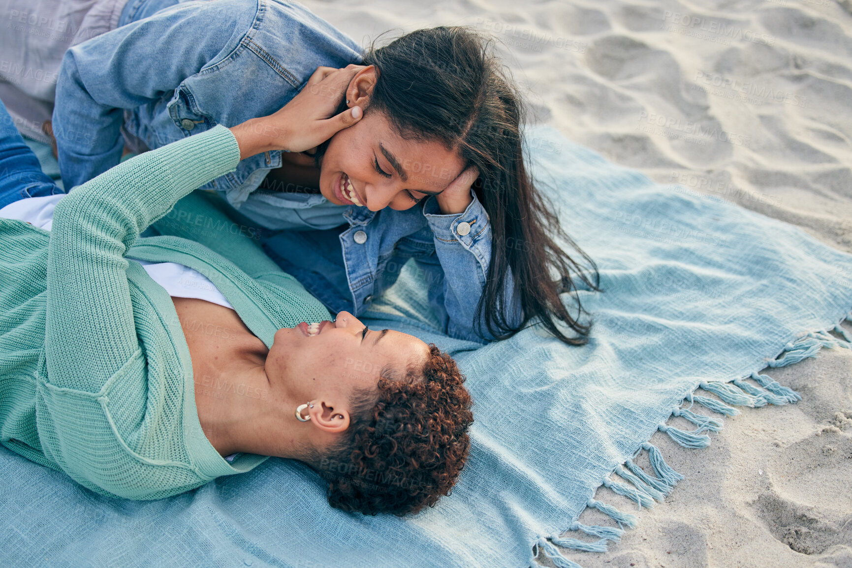 Buy stock photo Love, picnic and smile, lesbian couple on blanket together, holding hands on sand and holiday adventure. Lgbt women, bonding and relax on ocean vacation with romance, pride and happy lying in nature.