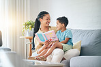Book, love and mother with kid on sofa for storytelling in living room of happy home, teaching and bonding fun. Reading, learning and mom with child, fantasy story on couch and quality time together.