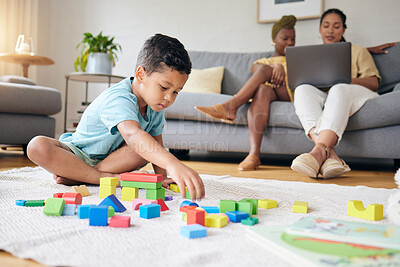 Buy stock photo Play, toys and child on floor with parents on sofa for learning, development and education. Lgbtq family, home and boy with building blocks for fun, relax and games with lesbian mothers on laptop