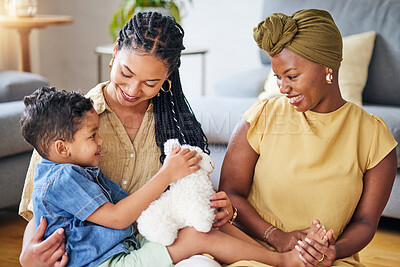 Buy stock photo Happy, gay family and child with a teddy bear on a home floor for development, fun and smile. Adoption, lesbian or LGBT women or parents and kid together in a lounge while playing with toys to relax