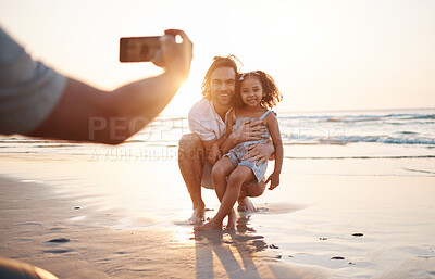 Buy stock photo Phone photography, father and daughter at beach, sunset sky and happy for memory, holiday and bonding. Smartphone, profile picture and man with girl child, hug and care for post, social media and sea