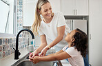 Mother, child and wash hands in home kitchen for good hygiene, health and wellness. Happy woman helping kid or daughter while learning skin care, cleaning and safety for germs or dirt at family house