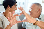 Heart shape, hands and senior couple bonding and talking in the living room of their home. Happy, smile and closeup of an elderly man and woman in retirement with a love sign or gesture together.