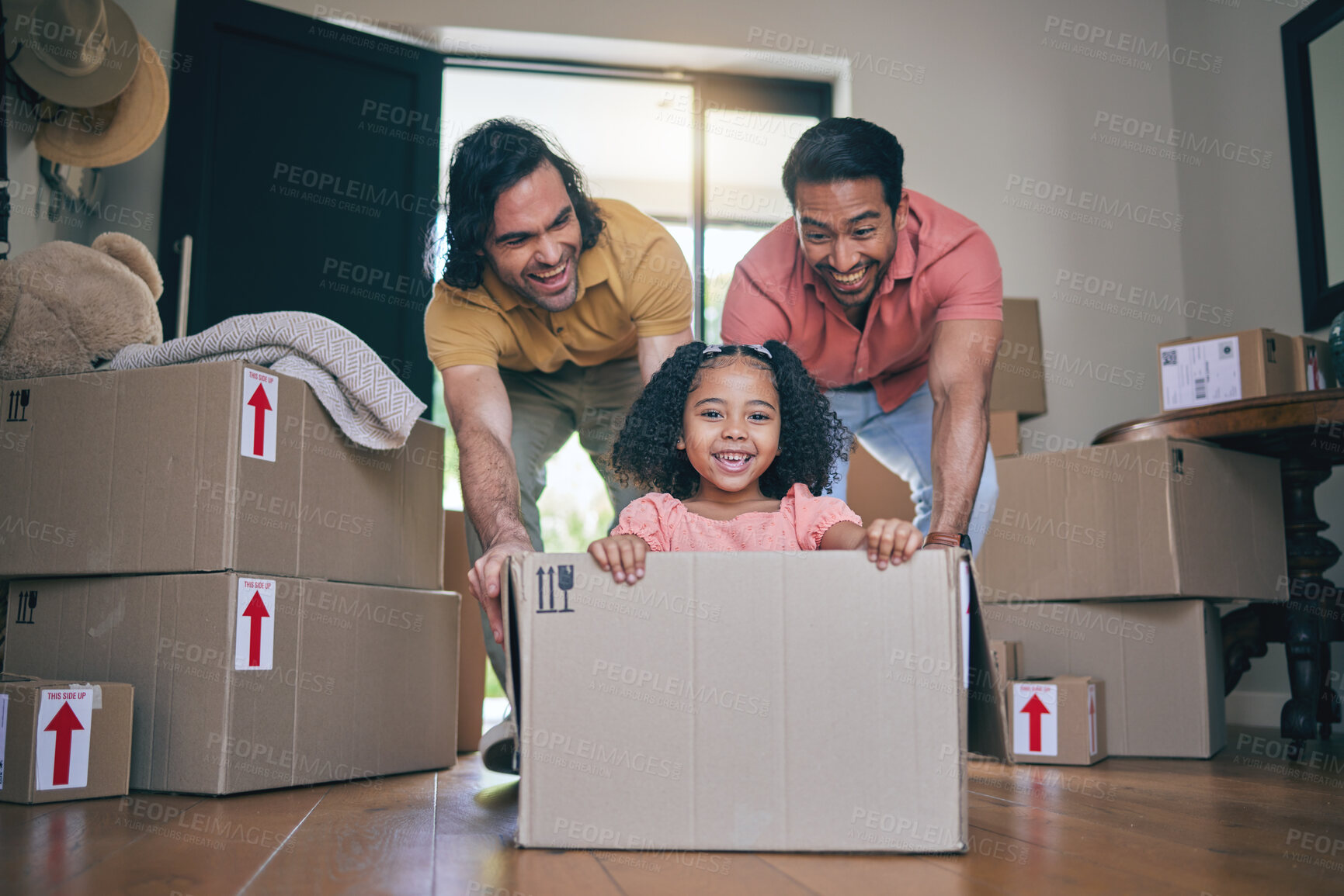 Buy stock photo Happy, family fun and box moving with child and gay parents in new home with cardboard package. Dad smile, kid and lgbt people together with youth game and property love in a house helping father