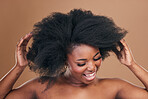 Beauty, hair and crazy with a model black woman in studio on a brown background for natural cosmetics. Face, smile and haircare with a playful young afro female person indoor for shampoo treatment