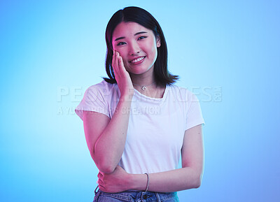 Buy stock photo Face, smile and Asian woman with beauty or dream with hope or happiness isolated in a studio blue background. Cute, shy and happy young female person with skincare or soft skin and with a memory