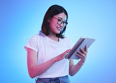 Buy stock photo Young woman, student and tablet for online education, e learning and study on blue, studio background. Happy person typing on digital technology, reading social media and school or youth information