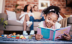 Child, toys and reading in home with knowledge development and building block in living room. Family, fun and youth learning with a young girl and parents in a house together with care and bonding