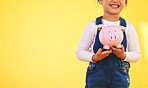 Girl kid, piggy bank and saving in studio with smile, mockup space and excited by yellow background. Young female child, money box and start investment for promo, financial knowledge or future goal