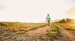 Sun flare, farm and man with agriculture, countryside and walking with grass field, nature and fresh air. Person, farmer and guy with growth, industry and landscape with sustainability or environment