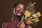 Skincare, smile and protea with the face of a black woman in studio on brown background for natural treatment. Beauty, plant or cosmetics and a young model indoor for aesthetic wellness with flowers