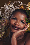 African woman, plants and thinking in studio with flowers for beauty, wellness or natural glow by brown background. Girl, model and face with leaves, ideas and memory for cosmetics, skin or aesthetic