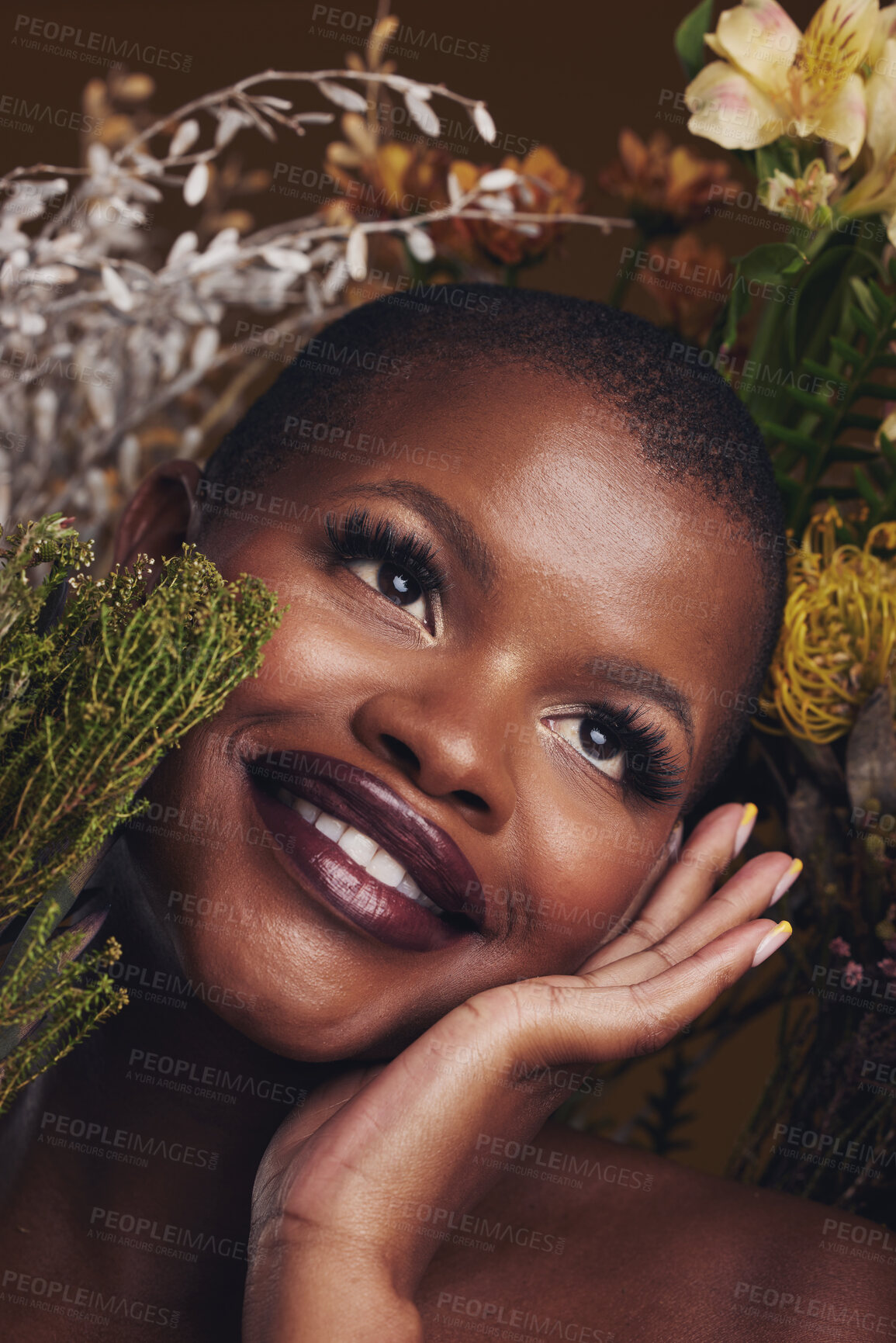 Buy stock photo Beauty, cosmetic and black woman with flowers in a studio for natural face makeup for cosmetology. Happy, smile and young African female model with floral aesthetic isolated by a brown background.