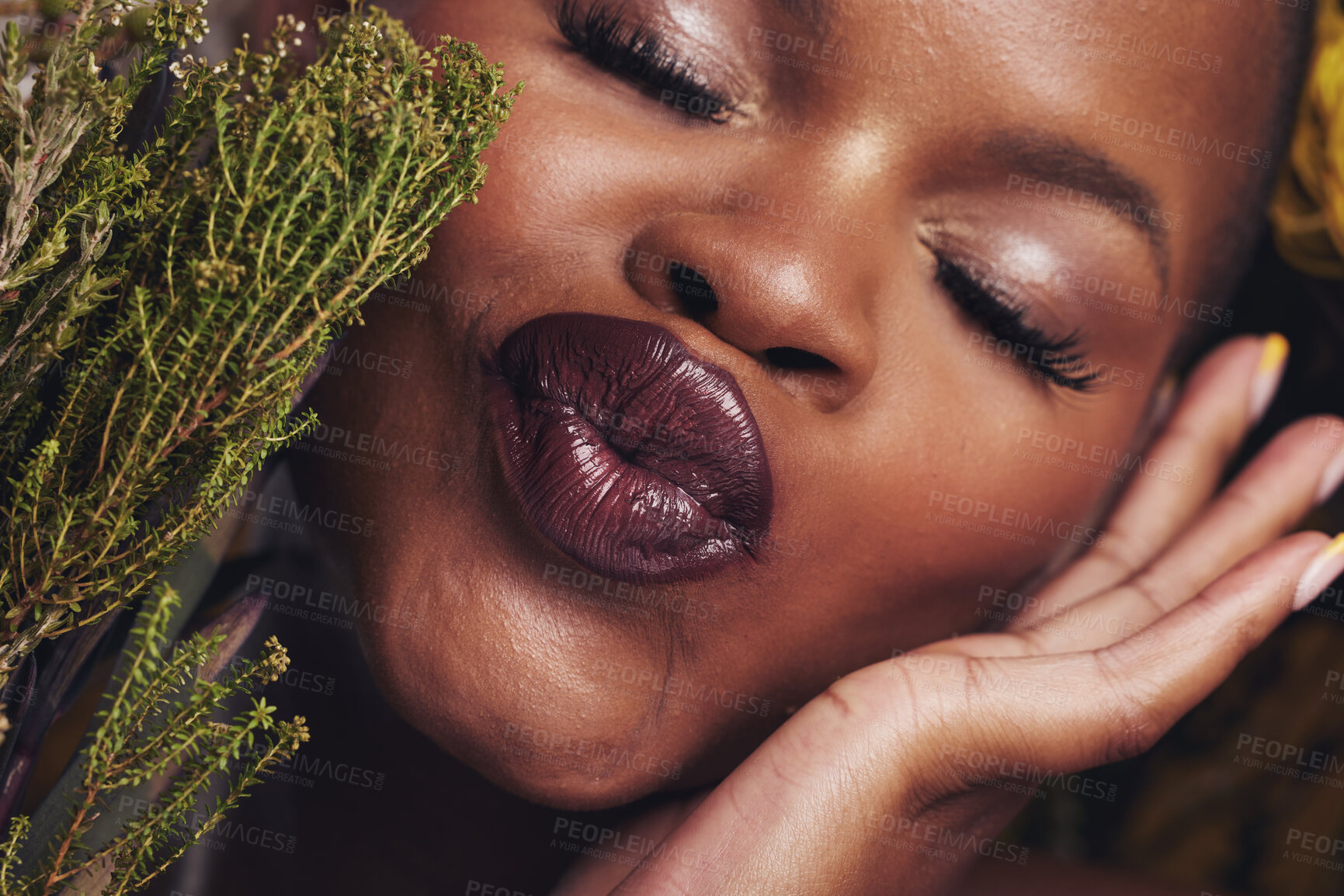 Buy stock photo African woman, plants and makeup in studio with kiss, beauty and wellness with lipstick, skin and closeup. Girl, model and face with leaves, pouting or happy for cosmetics, shine or aesthetic in zoom