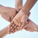 Blue sky, hands stack and together for team building motivation, group cooperation or community goals support. Closeup below view, synergy commitment and people collaboration, teamwork and solidarity