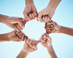 Hands, fist and people in circle with low angle for trust, solidarity and motivation on blue sky background. Power, hands and friends collaboration with hope, community and support of goal or mission